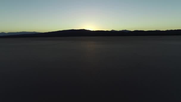 Cena de drones aéreos de deserto plano seco, estranha formação geológica deserta ao pôr-do-sol. Barreal da província de Arauco Rioja, Argentina. Vista geral ascendente de montanhas e casas — Vídeo de Stock