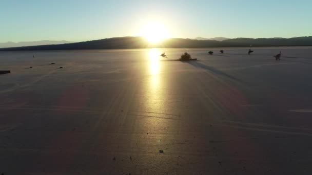 Cena de drone aéreo ao pôr-do-sol no deserto de avião descobrindo torre de vigia de madeira. Reflexão solar sobre o deserto plano. Barreal de Arauco, Aimogasta, província de Rioja, Argentina — Vídeo de Stock