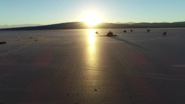 Escena aérea de drones al atardecer en el desierto plano descubriendo una torre de vigilancia de madera. Reflejo solar sobre el desierto plano. Barreal de Arauco, Aimogasta, Provincia de Rioja, Argentina — Vídeo de stock