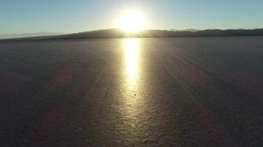 Kuru parlak toprak kırık batımında ufukta doğru uçan hava dron sahne. Güneş desertic yüzeyi üzerine yansıtır. Barreal de Arauco, Aimogasta, Rioja Eyaleti, Arjantin