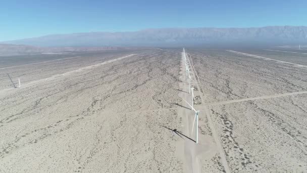 Escena aérea de drones de campo de viento lleno de aerogeneradores alineados en Aimogasta, la rioja, Argentina. Generación de energía verde clara sostenible. Cámara bajando. Las montañas de los andes en el fondo . — Vídeo de stock