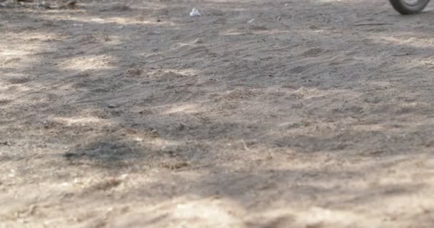 Détail de route de gravier et roue de vélo passant très vite. De la poussière dans l'air. Course cycliste à Londres, Province de Catamarca, Argentine . — Video