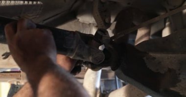 Mekanik tamir, kardan conection yaşlı arabada fark için temizlik. Eller bir adam olay yerinde görünür