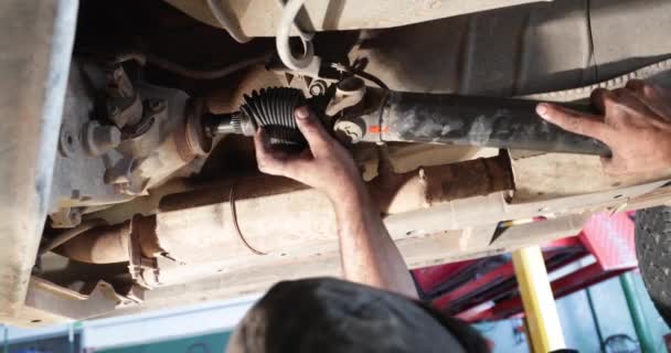 Mechanic joining the cardan to the differential. Man hands can be seen while working in the car. — Stock Video