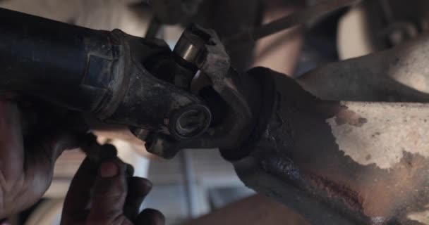 Механический ремонт кардана. Человек устанавливает кольцо для крепления универсального поперечного сустава к кардану. На сцене появляются грязные руки. — стоковое видео