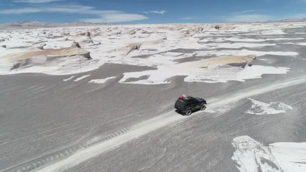 Drohnen-Szene eines Geländewagens in der grauen Wüste, umgeben von weißen natürlichen Felsbrocken des Bimssteinfeldes. antofagasta de la sierra, katamarca, argentina — Stockvideo