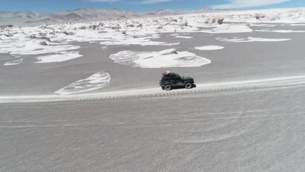 Escena aérea del dron del coche conduciendo fuera de la carretera en el desierto gris entre las esturcturas rocosas naturales blancas del campo de pómez. Antofagasta de la Sierra, Catamarca, Argentina — Vídeo de stock