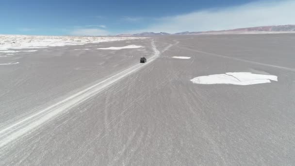 Escena aérea del dron del coche conduciendo fuera de la carretera en el desierto gris entre las esturcturas rocosas naturales blancas del campo de pómez. Antofagasta de la Sierra, Catamarca, Argentina — Vídeo de stock