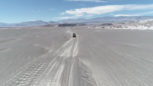Letecká drone scéně van jízda mimo silnici v sopečné oblasti, barevná suché oblasti. Černá postel lávy, bílá pemza šedé a poli erodované hory v pozadí — Stock video