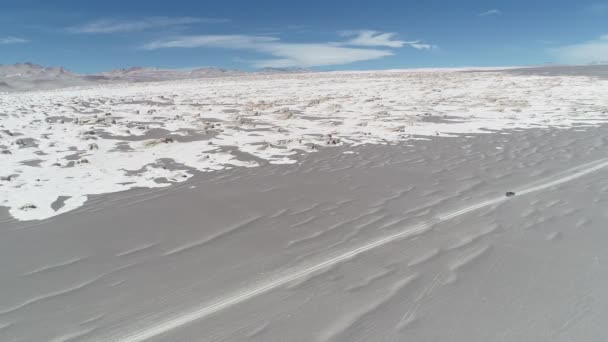 Luchtfoto drone scène van 4 x 4 busje rijden in grijze woestijn naast brede witte steenachtige puimsteen veld. Algemeen beeld van de vulkanische landschap van de desertic. Antofagasta de la Sierra, Catamarca, Argentina — Stockvideo