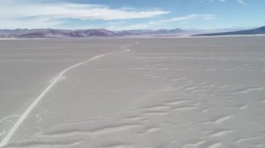 Geniş gri çöl, dağlar ve lav siyah yatak arasında yol geçiş kapalı hava dron sahne. Genel görünümden yere inen. Antofagasta de la Sierra, Catamarc, Argentina