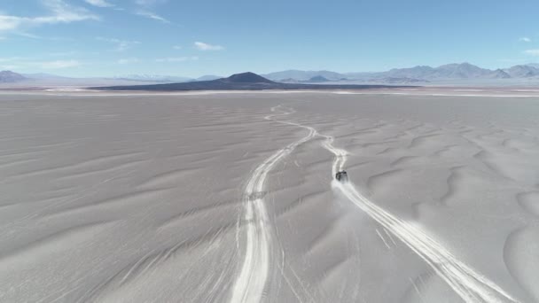 Luchtfoto scène van busje rijden tussen de zandduinen Off-Road in vulkanische woestijngebied. Spectaculaire zwarte Carachi Pampa vulkaan bij achtergrond. Expeditie in dorre landschap. Catamarca, Argentinië — Stockvideo