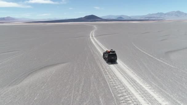 Antenowe sceny szczegółowości van jazdy między wydmy off road w wulkanicznym regionie pustyni. Spektakularne czarny wulkan Carachi Pampa w tle. Wyprawa w krajobraz. Catamarca, Argentyna — Wideo stockowe