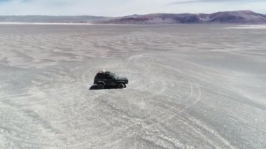 Hava dron sahne sefer 4 x 4 van geniş desertic bölgesinde bir kumul üzerinde. Kamera uçuş araç etrafında bir daire içinde. Antofagasta de la sierra, Catamarca, Argentina