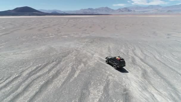 Légi jelenet van vezetés off road, sivatagi vulkanikus régióban, a megálló autó. Látványos fekete Carachi Pampa vulkán a háttérben. Expedíció, Kopár táj. Catamarca, Argentína — Stock videók