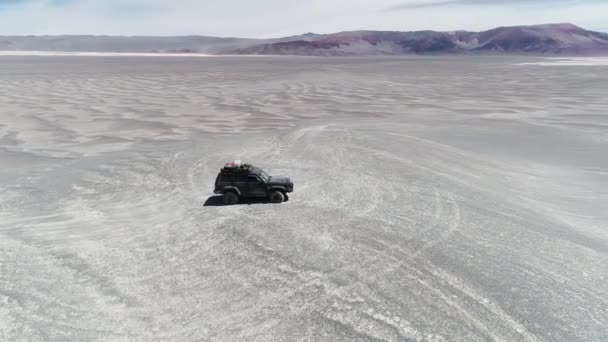 Luchtfoto drone scène van ISS Expeditie 4 x 4 busje over een duin in brede desertic regio. De vlucht van de camera in een cirkel rond de auto. Antofagasta de la sierra, Catamarca, Argentina — Stockvideo