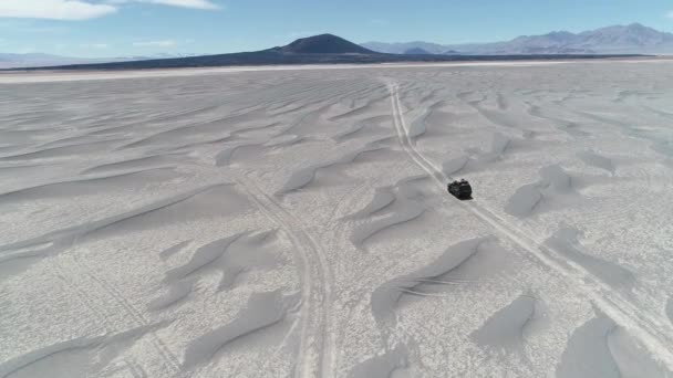 Luchtfoto scène van detail van busje rijden tussen de zandduinen Off-Road in vulkanische woestijngebied. Spectaculaire zwarte Carachi Pampa vulkaan bij achtergrond. Expeditie in dorre landschap. Catamarca, Argentinië — Stockvideo