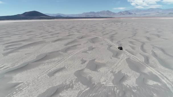 Antenowe sceny szczegółowości van jazdy między wydmy off road w wulkanicznym regionie pustyni. Spektakularne czarny wulkan Carachi Pampa w tle. Wyprawa w krajobraz. Catamarca, Argentyna — Wideo stockowe