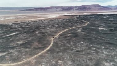 Lav, siyah lapillis, karanlık desertic bölge yataklar arasında off road sürüş 4 x 4 sefer van hava sahne. Arka plan Dağları renkler kırmızı. Hissettirilecek çorak manzara. Catamarca, Arjantin 