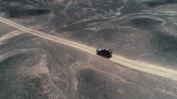 Senital luchtfoto drone scène van 4 x 4 expeditie busje rijden via onverharde weg op zwarte vulkanische woestijn. Bed van lava. Antofagasta de la sierra, Catamarca, Argentina — Stockvideo