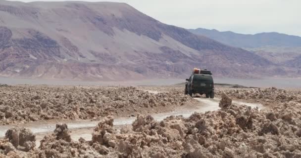 4x4 van traveling off road in dirty salt field. Desertic landscape with colored mountains at background. Antofagasta de la sierra, Catamarca, argentina — Stock Video