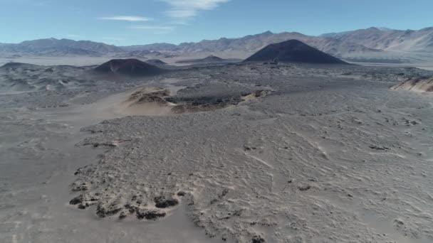 Scena aerea drone di ampia regione vulcanica. Vulcani rossi e neri in un paesaggio desertico grigio. Volando sopra un letto di lava. Antofagasta de la Sierra, Catamarca, Argentina — Video Stock