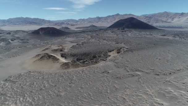 Antenowe drone scena szeroko wulkanicznego regionu. Czarno -czerwone wulkany w szary desertic krajobraz. Latające nad łożem lawy. Antofagasta de la Sierra, Catamarca, Argentyna — Wideo stockowe