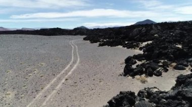 Lav siyah yatak üzerinde uçan hava dron sahne. Doğal volkanik dokular, desenleri. arka plan dağlar ve çöl. Antofagasta de la Sierra, Catamarca, Argentina