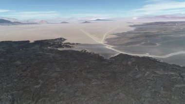 Lav siyah yatak üzerinde uçan hava dron sahne. Arka plan çeşitli koniler ile volkanik desertic manzara. Doğal volkanik dokular, desenleri. Antofagasta de la Sierra, Catamarca, Argentina