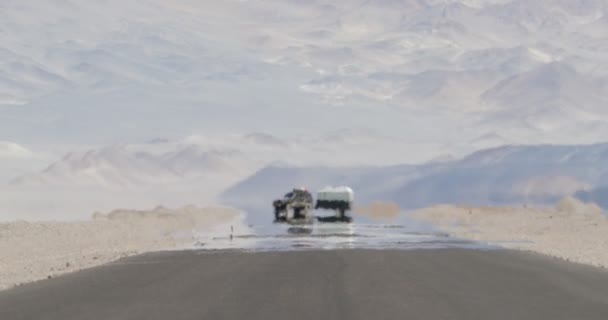 Escena fija de furgoneta 4x4 con caravana que viaja por carretera con efecto de neblina de calor en el desierto y la región seca montañosa. Ilusión de vapor de agua. Mirage. Antofagasta de la Sierra, Catamarca, Argentina — Vídeo de stock