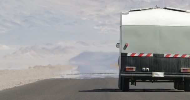 Escena fija de furgoneta 4x4 con caravana que viaja por carretera con efecto de neblina de calor en el desierto y la región seca montañosa. Ilusión de vapor de agua. Mirage. Antofagasta de la Sierra, Catamarca, Argentina — Vídeo de stock