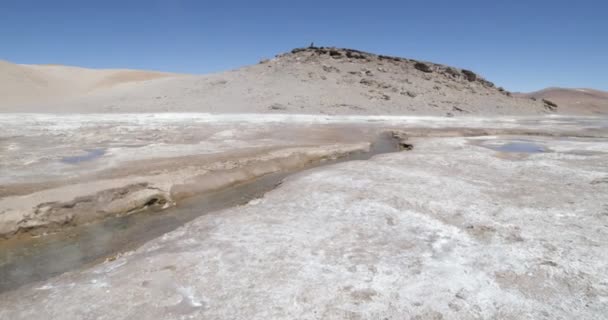 Walking along hot meandric river with water vapor ascending. 4x4 vans at background. Volcan Galan expedition, Antofagasta de la Sierra, Catamarca, Argentina — Stock Video