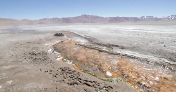 Chodzenie wzdłuż gorącej pomarańczowej rzeki meandric z pary wodnej rosnąco. Zbliżenie strumienia. Ekspedycja Volcan Galan, Antofagasta de la Sierra, Catamarca, Argentyna — Wideo stockowe