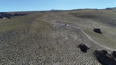 4 x 4 van, parkur Caddesi üzerinde otlar ve yaşlı kayalar ile yüksek dağın altın manzaraya hava dron sahne. Galan volkan gezi, Antofagasta de la Sierra, Catamarca, Argentina.