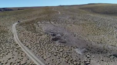 4 x 4 van, parkur otlar ve yaşlı kayalar ile yüksek dağın altın manzaraya yoldan sürüş hava dron sahne. Galan volkan gezi, Antofagasta de la Sierra, Catamarca, Argentina.