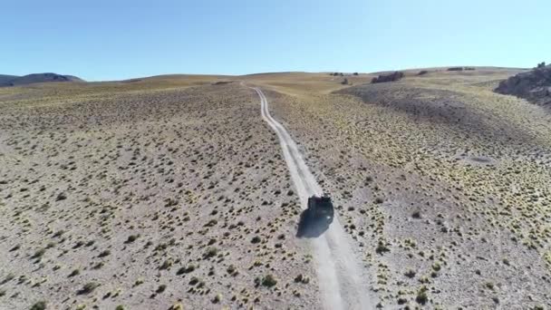 Cena de drone aéreo, câmera rastreando 4x4 van na paisagem estepe, Antofagasta de la Sierra. Caminho de cascalho, estrada. Galan vulcano excurision at Catamarca Province, Argentina. Manhã luz, poeira no ar . — Vídeo de Stock