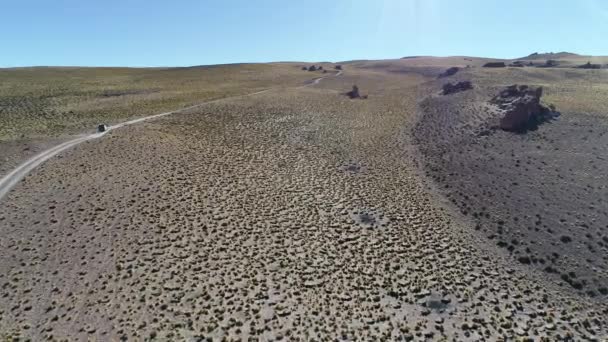 Aerial drone scene of 4x4 van driving at track off road at golden landscape of high mountain with grasses and old rocks. Galan volcano excursion,  Antofagasta de la Sierra, Catamarca, Argentina. — Stock Video