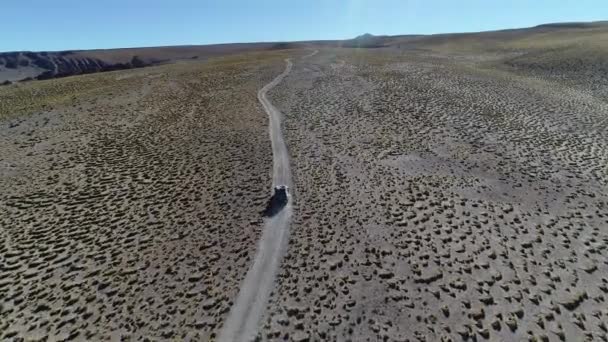 Aerial drone scene of 4x4 van driving at track off road at golden landscape of high mountain with grasses and old rocks. Galan volcano excursion,  Antofagasta de la Sierra, Catamarca, Argentina. — Stock Video