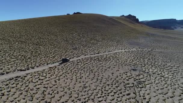 Scena aerea drone di 4x4 van guida in pista fuori strada al paesaggio dorato di alta montagna con erbe e vecchie rocce. Escursione vulcano Galan, Antofagasta de la Sierra, Catamarca, Argentina . — Video Stock