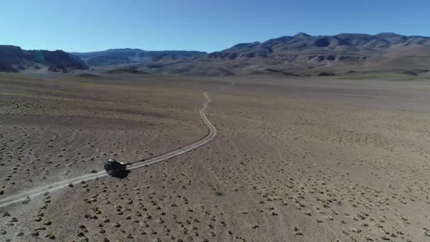Scène aérienne de drone de fourgon 4x4 conduisant à la piste hors route au paysage doré de haute montagne avec des herbes et de vieilles roches. Excursion au volcan Galan, Antofagasta de la Sierra, Catamarca, Argentine . — Video
