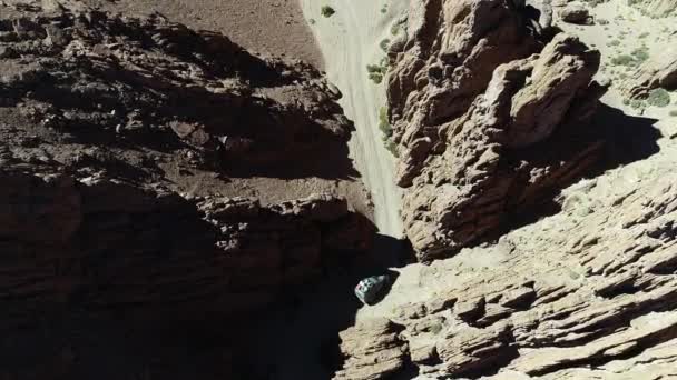 在一个狭窄的红色峡谷中, 四轮驱动面包车驶离公路的令人感觉的空中无人机场景。加兰火山游览, 安托法加斯塔巴-德拉谢拉, 卡塔马卡, 阿根廷 — 图库视频影像
