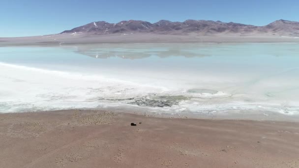 阿根廷阿塔卡马省加兰火山的 Diamante 泻湖空中无人机场景。相机向后移动, 发现咸水上的景观反射。海岸四轮驱动面包车停放 — 图库视频影像