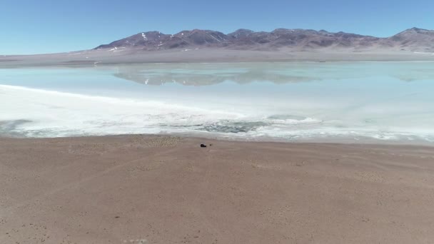 Escena aérea del dron de la Laguna Diamante en el volcán Galán en la provincia de Catamarca, Atacama, Argentina. Cámara avanzando descubriendo refelcciones de paisaje en agua salada. Aparcamiento furgoneta 4x4 en la costa — Vídeos de Stock