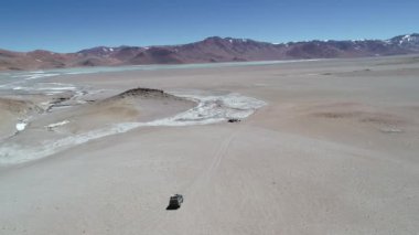 Beyaz sıcak nehir kenarında off road sürüş 4 x 4 van hava dron sahne. Diamante Volcan Galan krater gölünde. Antofagasta de la Sierra, Catamarca, Argentina