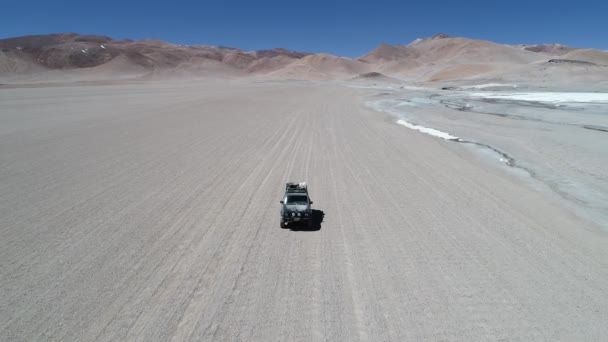 Aerial drone scene following 4x4 van from the front driving off road beside salty river in desertic landscape at Galan volcano crater.  Excursion in Antofagasta de la Sierra, Catamarca Argentina — Stock Video