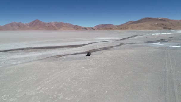 Scena aerea drone seguendo 4x4 van dal lato guida fuoristrada sul fiume salato nel paesaggio desertico al cratere vulcanico di Galan. Escursione ad Antofagasta de la Sierra, Catamarca Argentina — Video Stock