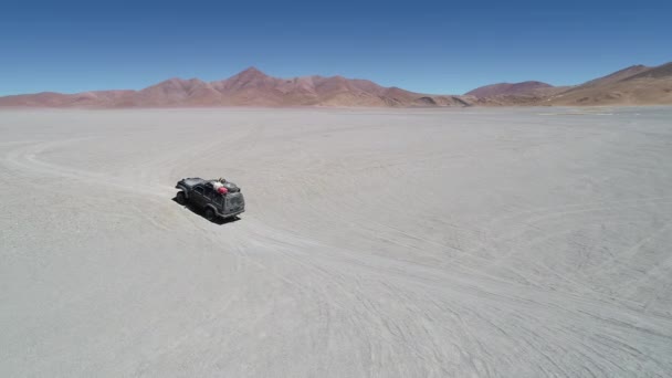 Drone антена сцени 4 x 4 Ван водіння бездоріжжю в сірий широкі пустелі з барвистим гір у фоновому режимі. Галан вулканічний кратер. Екскурсія Антофагаста де-ла-Сьєрра, Катамарка, Аргентина — стокове відео