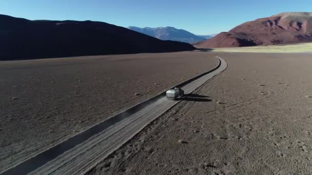 Escena aérea de drones de 4x4 con caravana que viaja fuera de la carretera en pista de grava en montañas desérticas. Andes al fondo. Antofalla, Catamarca, Argentina — Vídeos de Stock