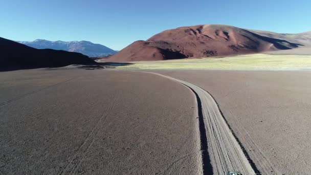 Antena Drone sceny van z karawaną podróży Off Road na torze żwirowym na pustyniach gór. Pojawia się samochód, po samochodzie od tyłu. Andes w tle. Antofalla — Wideo stockowe
