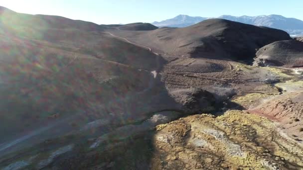 Vzdušný všeobecný výhled sestupuje přes vlhké údolí kolem pouště rozervovaných hor při západu slunce. Hnusné, nákresy a vegetace. Zlatá hodina, světlice a světlo hlasitosti. Antofalla, Katamarca — Stock video